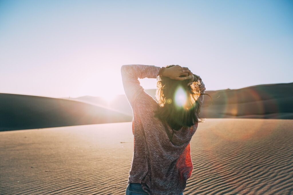 a woman stares into the sun in the desert