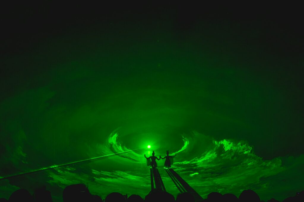 two shadowy figures fly through a green sky