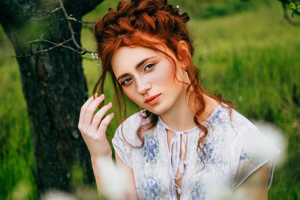 portrait of a red-haired woman with an updo and flower shirt